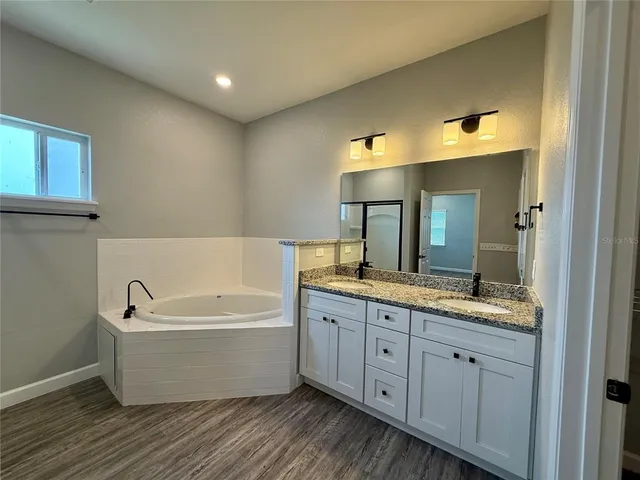 a bathroom with a double vanity sink mirror and bathtub