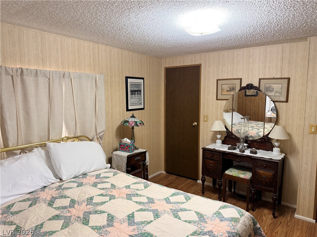 1391 West Dyer Road Pahrump, NV 89048 - Photo 11 of 50 A comforting bedroom features warm wood-paneled walls and a classic vanity, perfect for restful evenings.