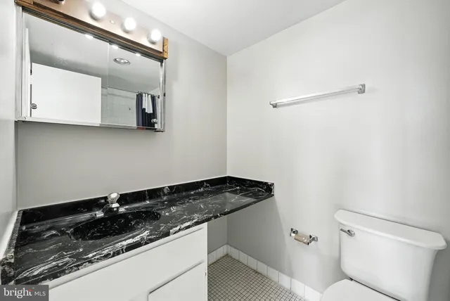 a bathroom with a granite countertop sink and a toilet