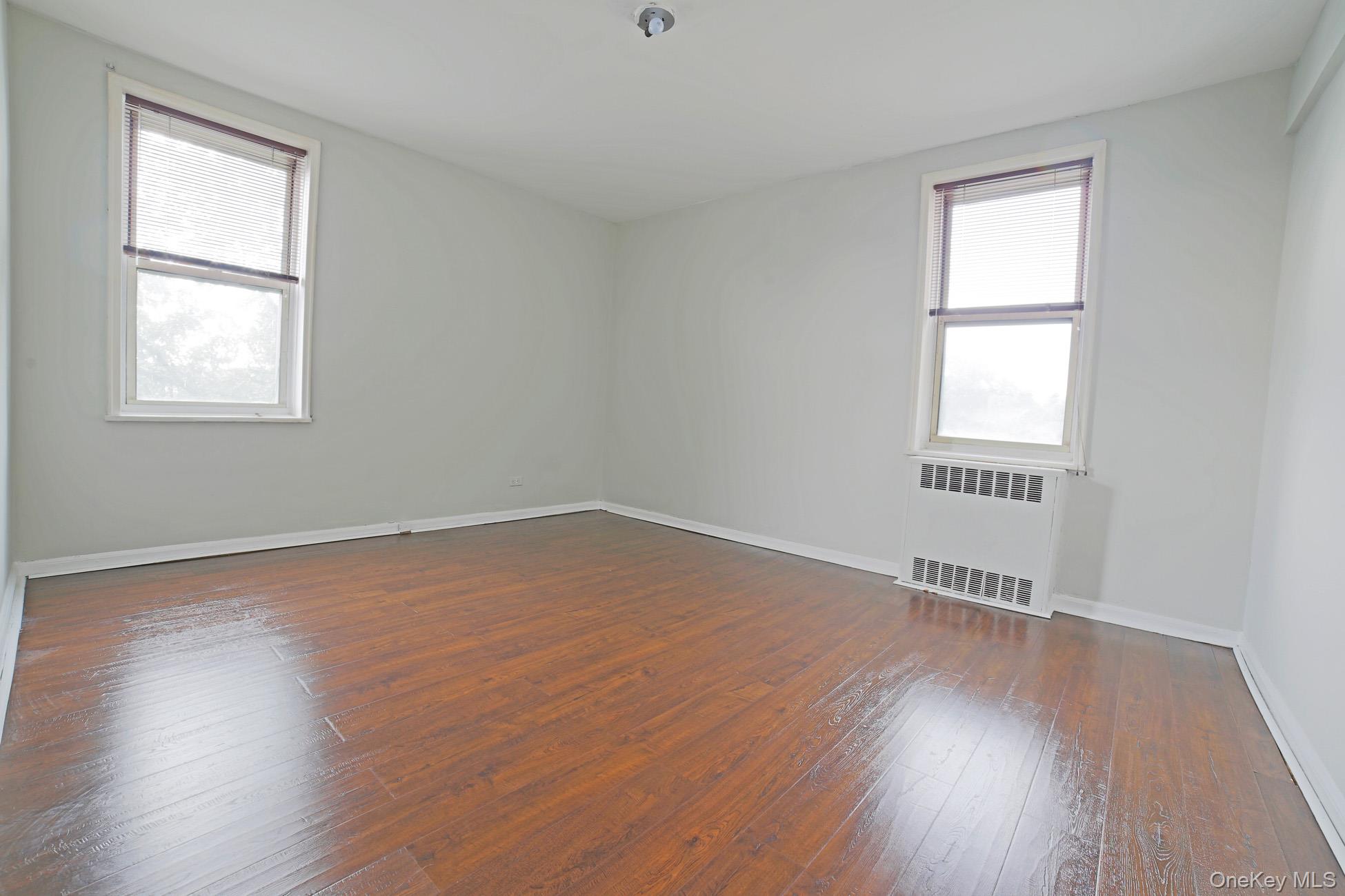 5621 Netherland Avenue, Unit 5C Bronx, NY 10471 - Photo 4 of 10 an empty room with wooden floor and windows