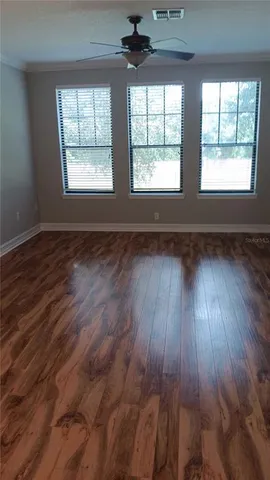 a view of an empty room with wooden floor and a window
