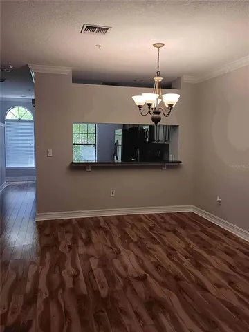 an empty room with wooden floor chandelier and windows