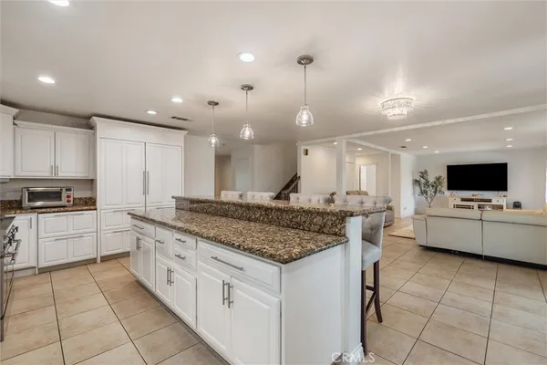 a large kitchen with granite countertop a large counter top a sink stainless steel appliances and cabinets
