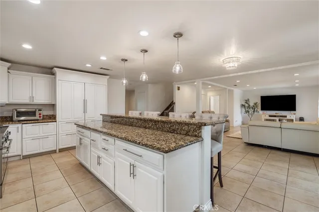 a large kitchen with granite countertop a large counter top a sink stainless steel appliances and cabinets