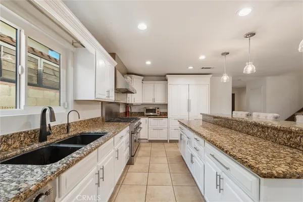 a kitchen with stainless steel appliances granite countertop a stove top oven a sink a dining table and chairs