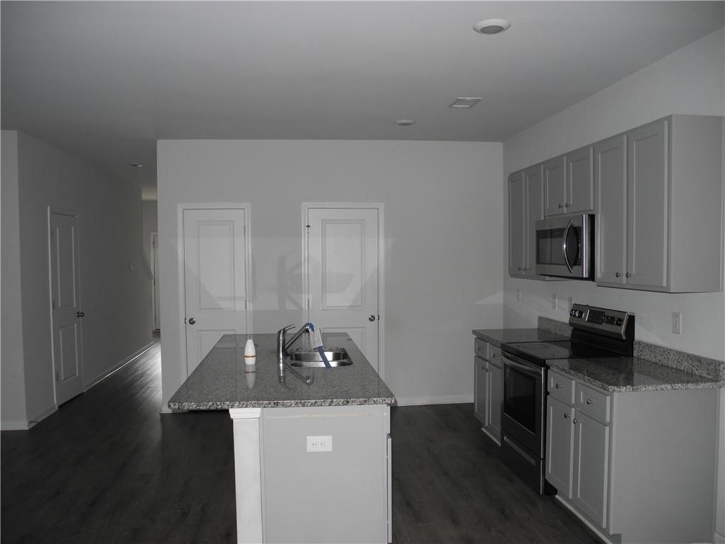 3353 Sable Elm Court Atlanta, GA 30349 - Photo 6 of 18 a kitchen with stainless steel appliances a stove a sink a microwave a refrigerator and cabinets