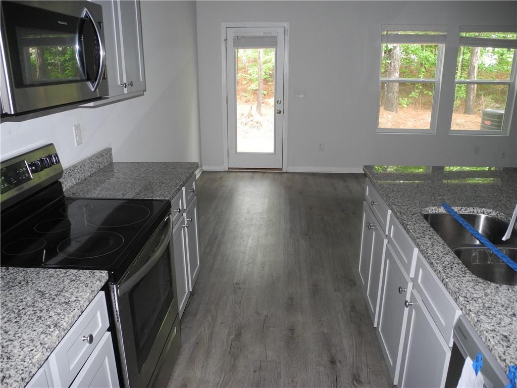 3353 Sable Elm Court Atlanta, GA 30349 - Photo 8 of 18 a kitchen with granite countertop a stove a sink and a microwave
