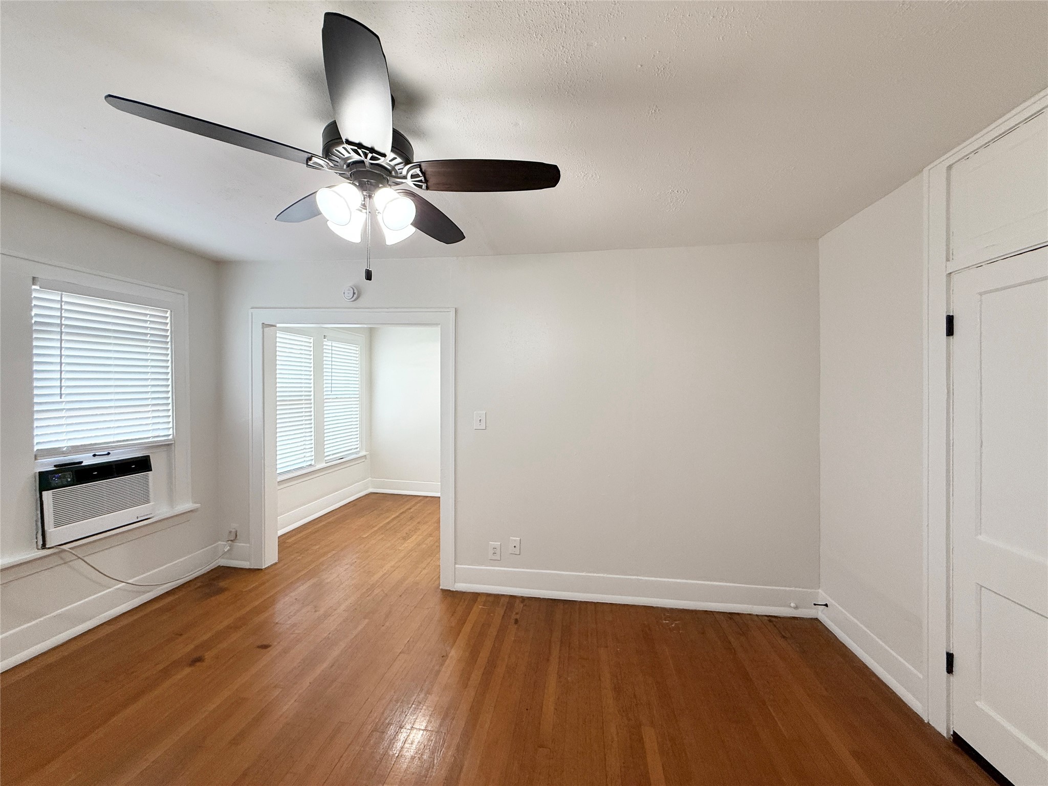 1126 Berthea Street, Unit 16 Houston, TX 77006 - Photo 3 of 16 an empty room with wooden floor chandelier fan and windows