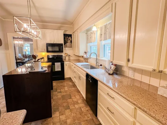 a large kitchen with kitchen island granite countertop a sink counter space appliances and a window