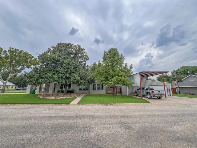 a view of a house with a yard and a large tree