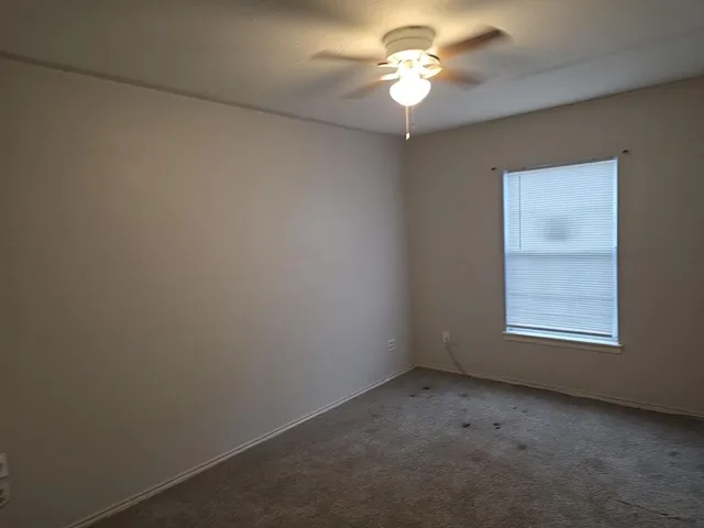 an empty room with a window and a fan
