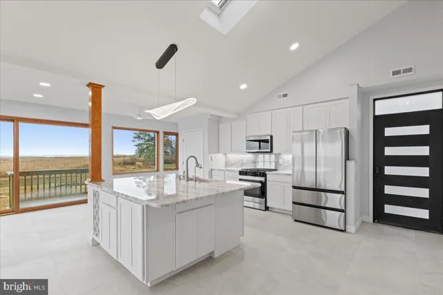 a large kitchen with kitchen island a large counter top appliances and a view of living room