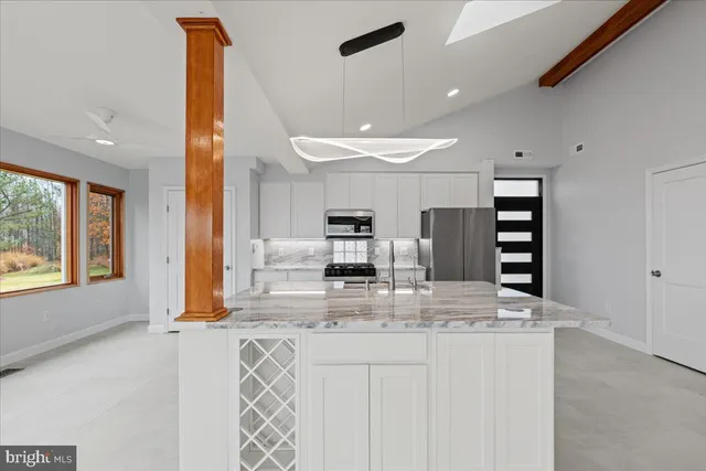 a large kitchen with kitchen island a large counter top appliances and a view of living room