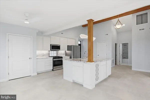 a view of kitchen with center island stainless steel appliances wooden floor and window