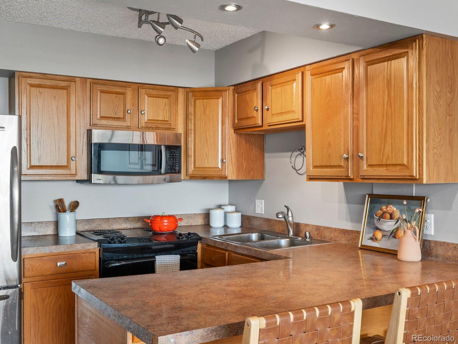 1850 Folsom Street, Unit 402 Boulder, CO 80302 - Photo 22 of 28 a kitchen with stainless steel appliances granite countertop a stove a sink dishwasher and a microwave with wooden cabinets