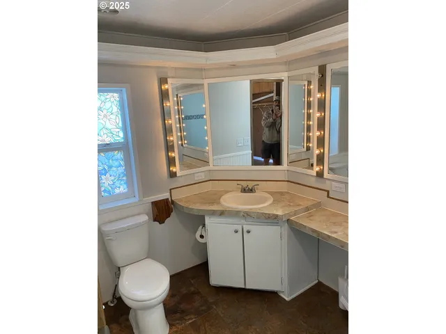 a bathroom with a granite countertop sink a toilet and mirror