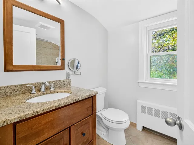 a bathroom with a granite countertop sink a toilet and a mirror