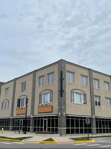 a front view of a building with streets and trees
