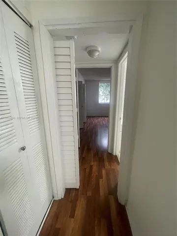 a view of a hallway with wooden floor and a bathroom