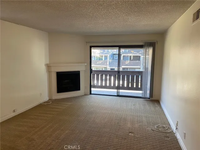an empty room with floor to ceiling windows and fireplace
