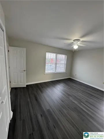 an empty room with wooden floor cabinet and windows