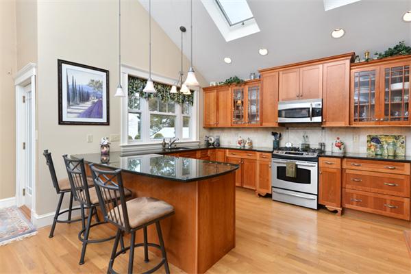 38 Jenness Street Quincy, MA 02169 - Photo 11 of 23 a kitchen with stainless steel appliances granite countertop a stove top oven a sink a dining table and chairs with wooden floor