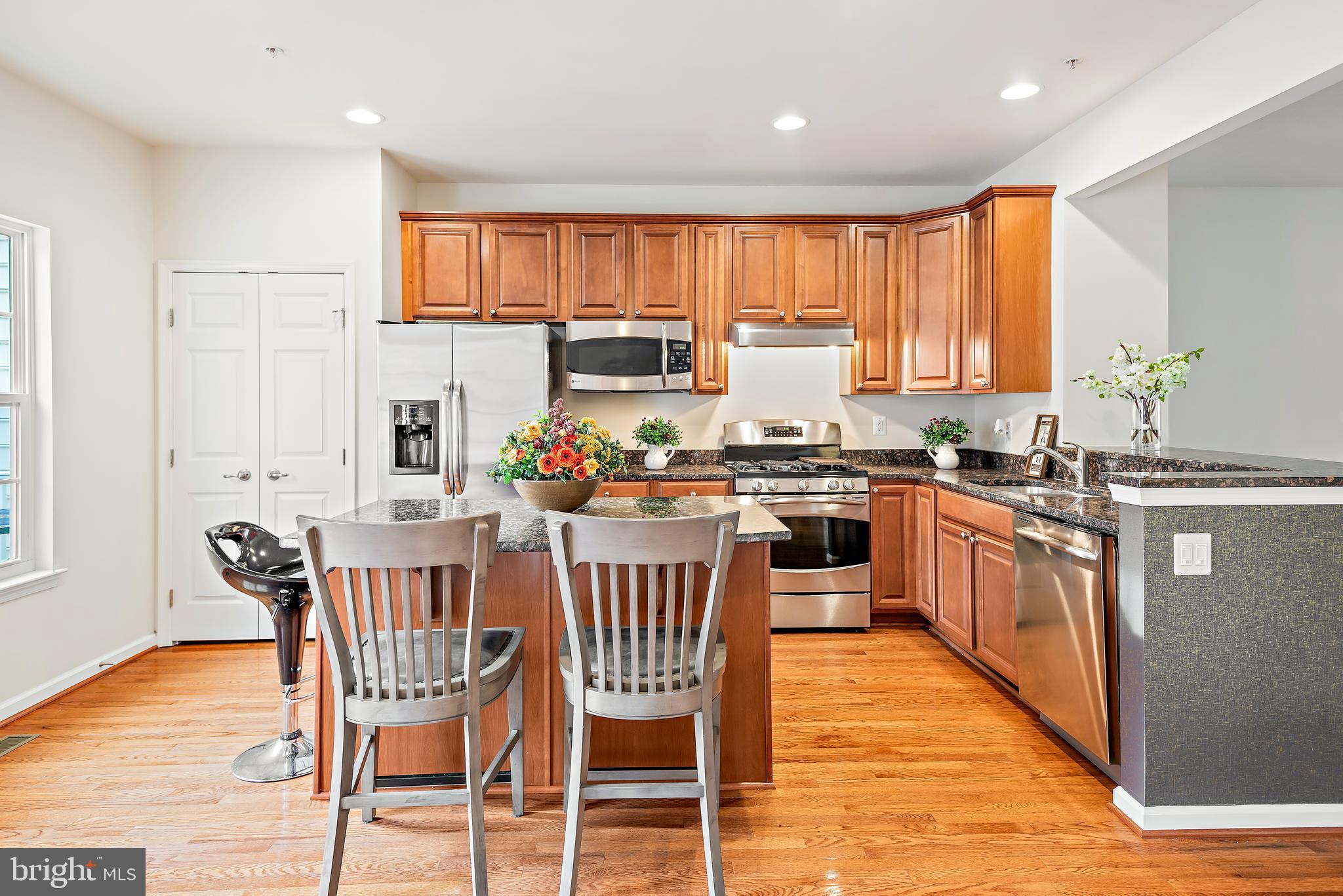 3838 Cullingworth Road Burtonsville, MD 20866 - Photo 31 of 69 a kitchen with stainless steel appliances granite countertop a stove top oven a sink dishwasher a dining table and chairs with wooden floor