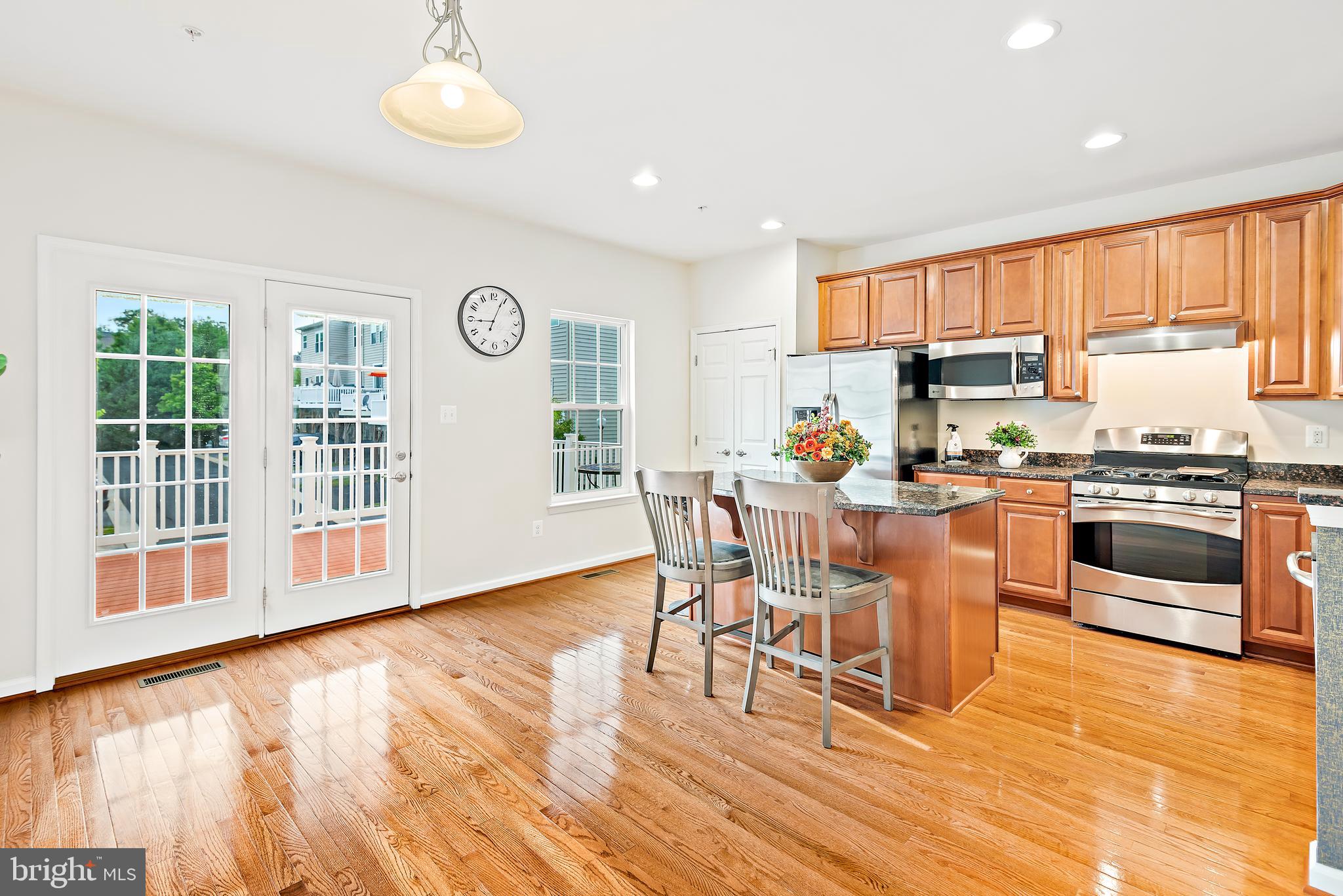 3838 Cullingworth Road Burtonsville, MD 20866 - Photo 35 of 69 a kitchen with stainless steel appliances granite countertop a stove top oven a refrigerator a dining table and chairs with wooden floor
