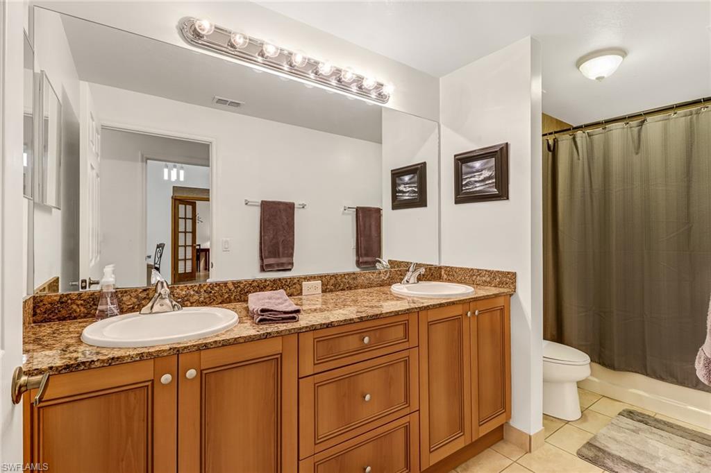 20301 Estero Gardens Circle, Unit 104 Estero, FL 33928 - Photo 15 of 43 a bathroom with a granite countertop sink toilet and mirror