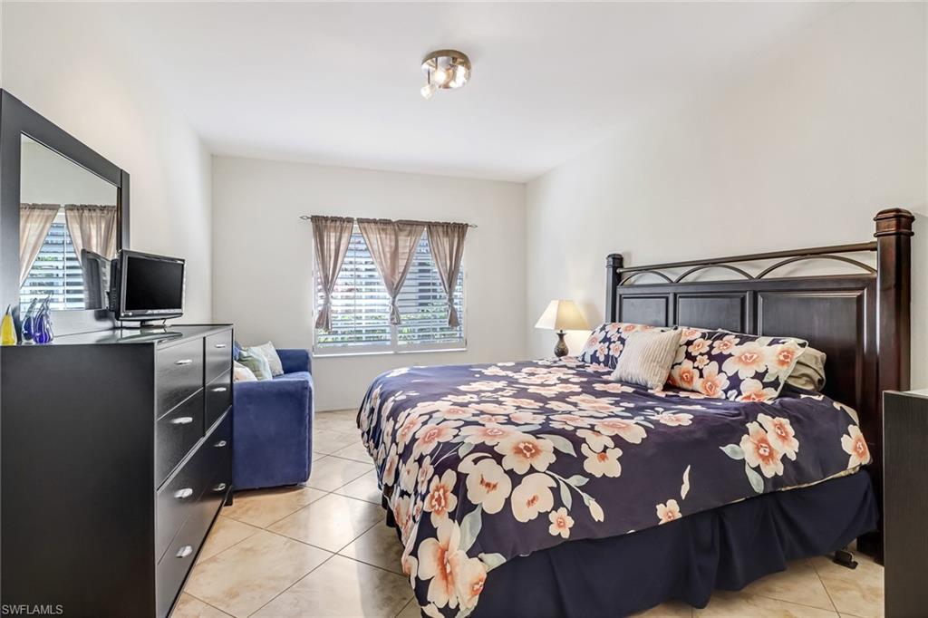 20301 Estero Gardens Circle, Unit 104 Estero, FL 33928 - Photo 16 of 43 a bedroom with a bed and flat screen tv