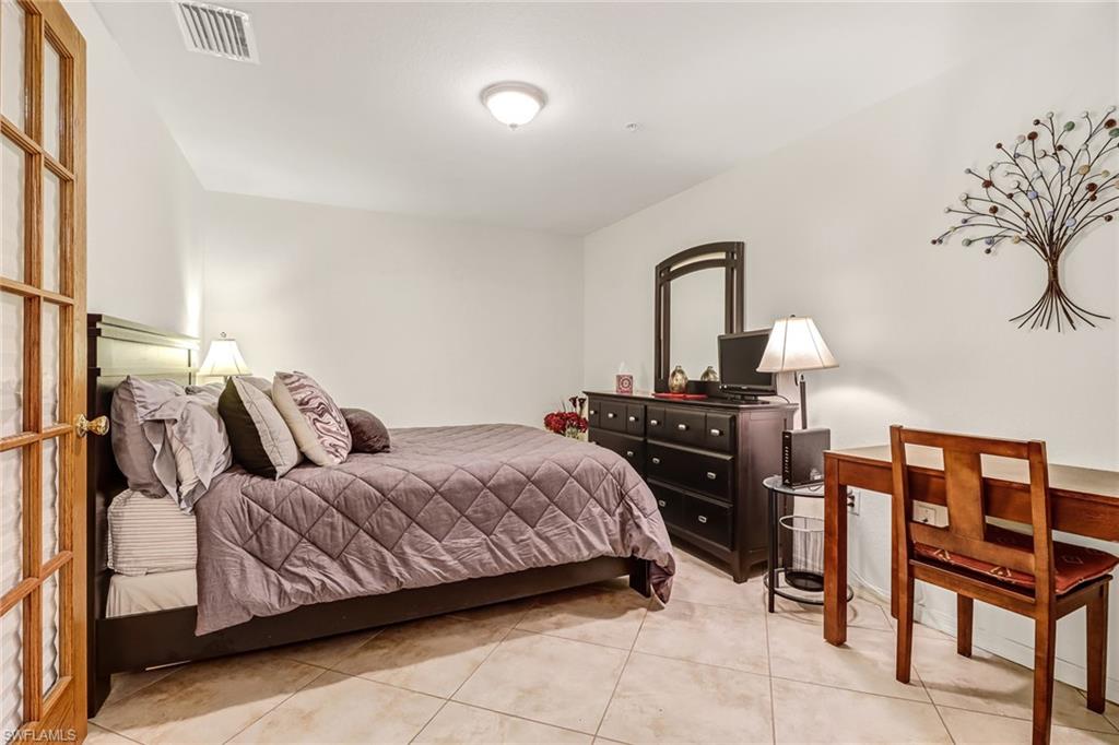20301 Estero Gardens Circle, Unit 104 Estero, FL 33928 - Photo 18 of 43 a bedroom with a bed and dresser with mirror