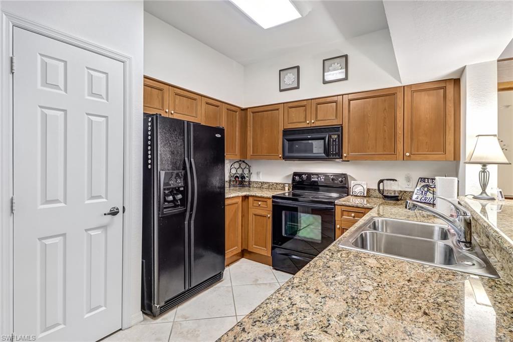 20301 Estero Gardens Circle, Unit 104 Estero, FL 33928 - Photo 5 of 43 a kitchen with stainless steel appliances granite countertop a refrigerator stove and sink