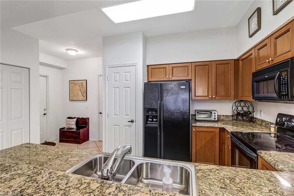 20301 Estero Gardens Circle, Unit 104 Estero, FL 33928 - Photo 6 of 43 a kitchen with granite countertop a refrigerator stove and sink