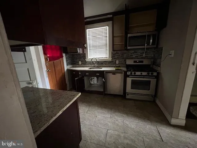 a kitchen with stainless steel appliances granite countertop a stove a sink and a microwave