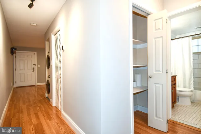 a view of a hallway with wooden floor and a bathroom