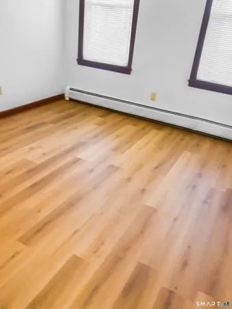 a view of an empty room with wooden floor and a window