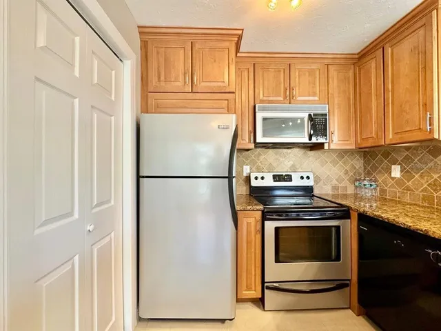 a kitchen with granite countertop cabinets stainless steel appliances and a window