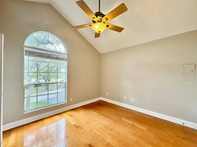 an empty room with windows and ceiling fan