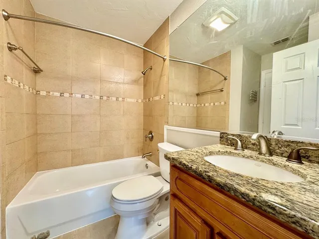 a bathroom with a granite countertop sink a toilet and bathtub