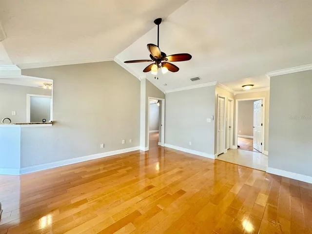a view of an empty room and chandelier fan