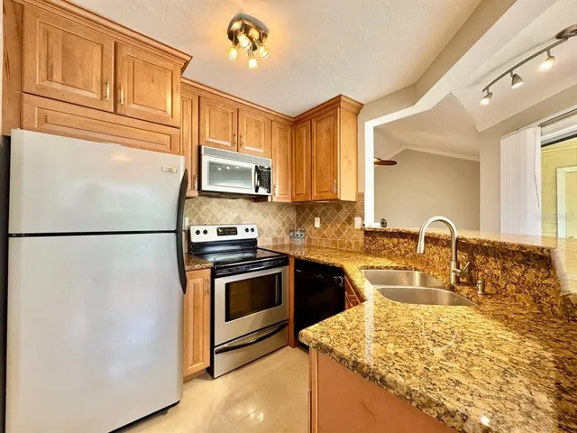 a kitchen with stainless steel appliances granite countertop a refrigerator sink stove microwave and cabinets
