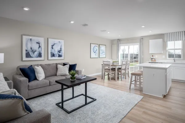 a living room with furniture a large window and wooden floor
