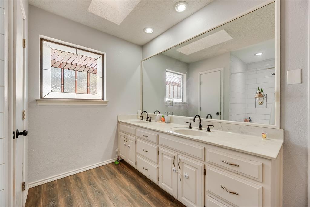 4102 Autumn Ridge Court Arlington, TX 76016 - Photo 16 of 20 Bathroom featuring a textured ceiling, a skylight, double vanity, dark wood-style floors, and a textured wall