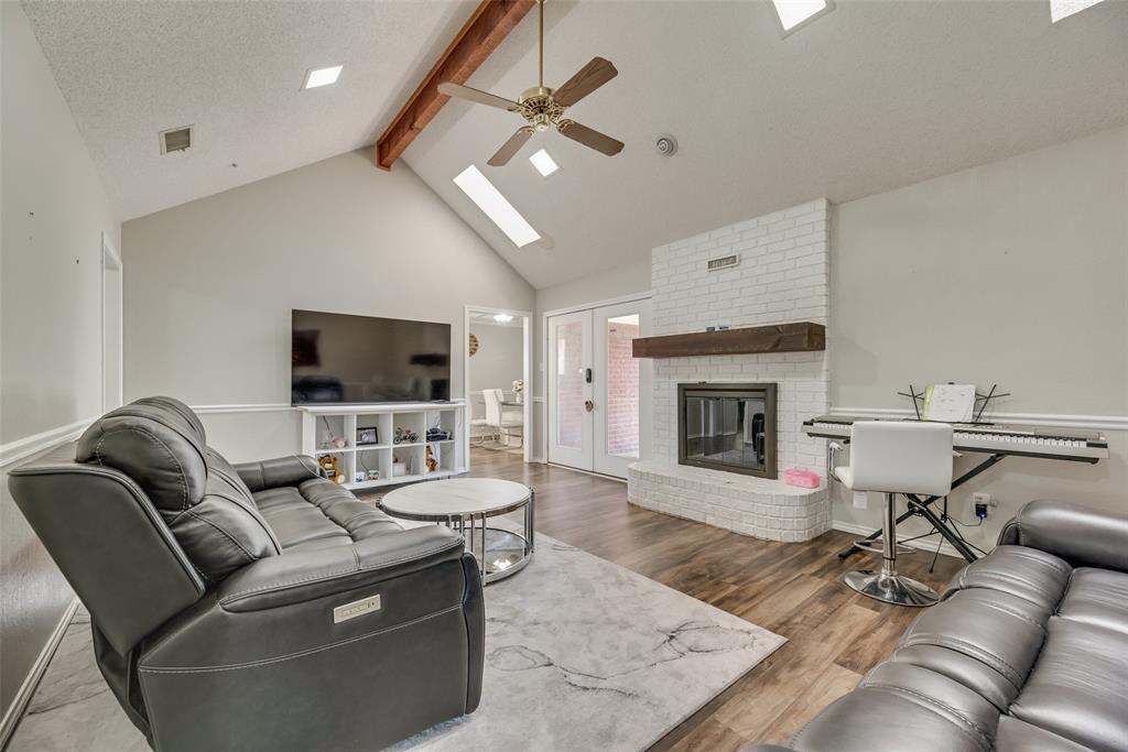 4102 Autumn Ridge Court Arlington, TX 76016 - Photo 3 of 20 Living area with beam ceiling, a skylight, wood finished floors, a brick fireplace, and high vaulted ceiling