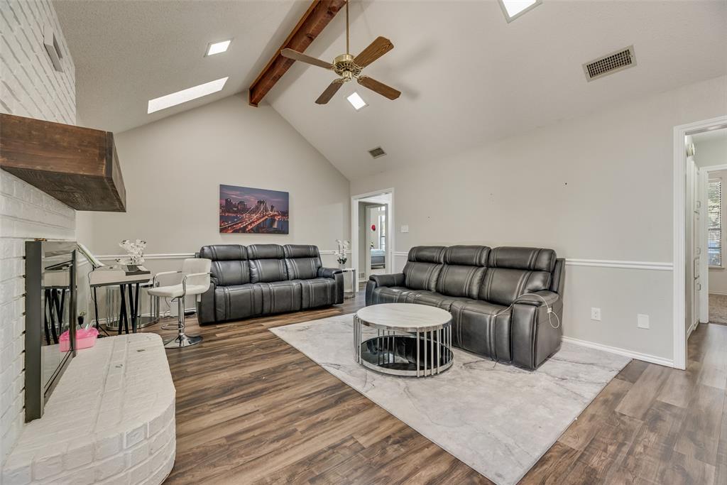 4102 Autumn Ridge Court Arlington, TX 76016 - Photo 4 of 20 Living room featuring a brick fireplace, a skylight, beam ceiling, ceiling fan, and wood finished floors
