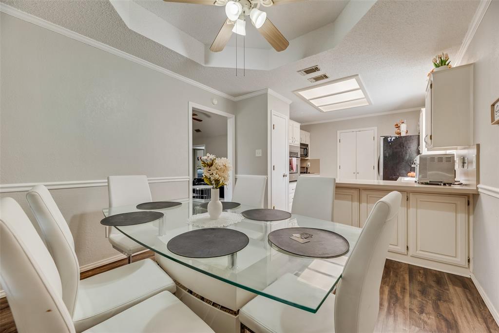 4102 Autumn Ridge Court Arlington, TX 76016 - Photo 6 of 20 Dining room with crown molding, dark wood-style floors, ceiling fan, a tray ceiling, and a textured ceiling