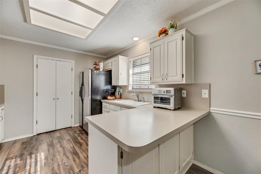 4102 Autumn Ridge Court Arlington, TX 76016 - Photo 7 of 20 Kitchen with a textured ceiling, white cabinets, light countertops, stainless steel fridge with ice dispenser, and crown molding