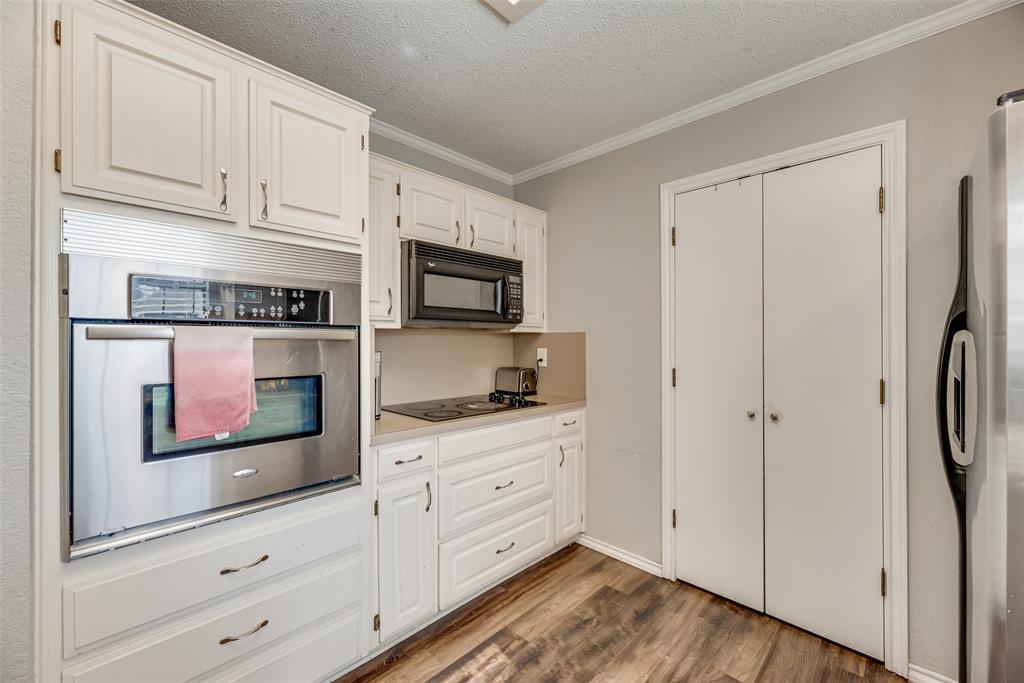 4102 Autumn Ridge Court Arlington, TX 76016 - Photo 8 of 20 Kitchen featuring wood finished floors, light countertops, black appliances, a textured ceiling, and white cabinetry