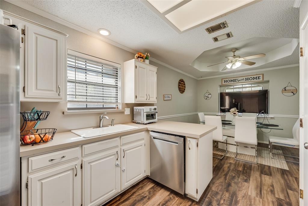 4102 Autumn Ridge Court Arlington, TX 76016 - Photo 9 of 20 Kitchen with a peninsula, a textured ceiling, light countertops, a tray ceiling, and crown molding