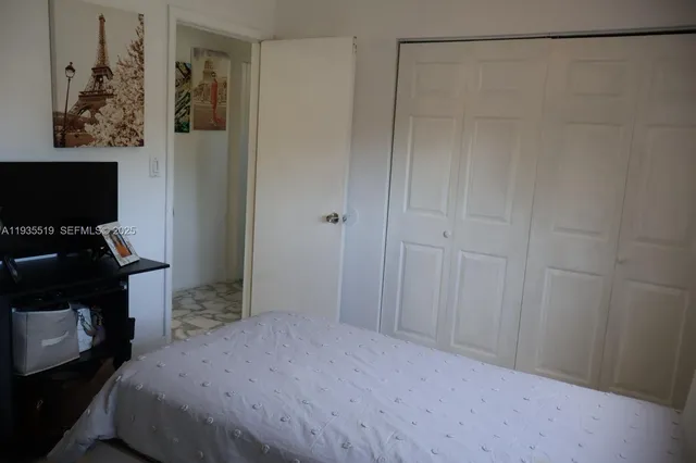 a bedroom with a bed and a flat tv screen on the dresser